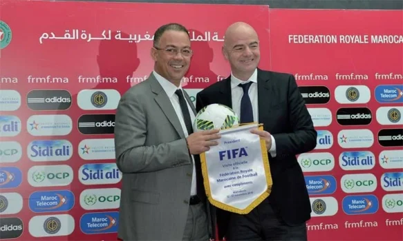 FIFA President Gianni Infantino and a Moroccan football official smiling and holding a FIFA pennant during a ceremony, highlighting Morocco’s rising influence in international football.