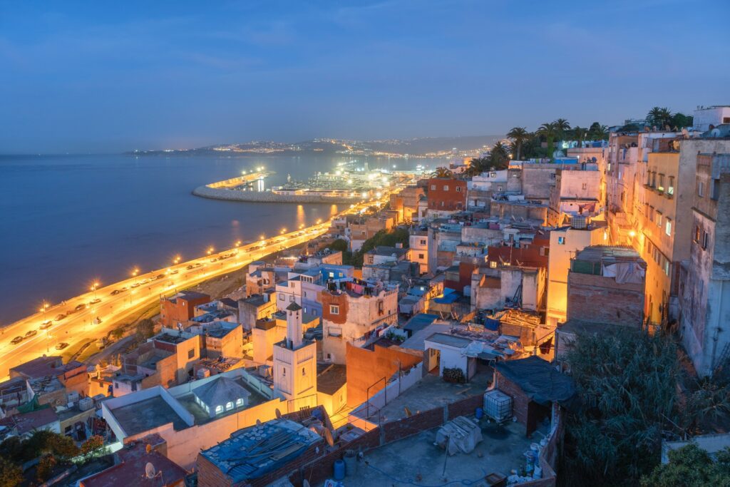 Evening view over Tangier’s coastline and old houses glowing with lights above the Mediterranean Sea