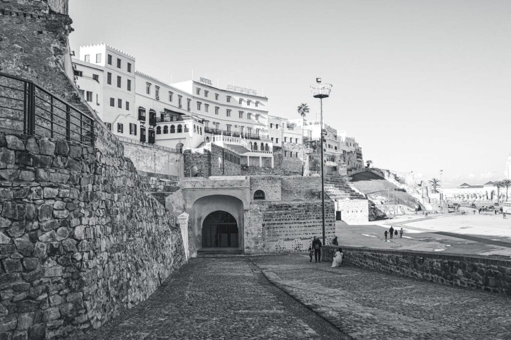 Stone pathway leading to the Kasbah entrance in Tangier with white buildings above and people walking nearby