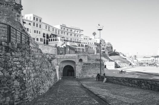 Stone pathway leading to the Kasbah entrance in Tangier with white buildings above and people walking nearby