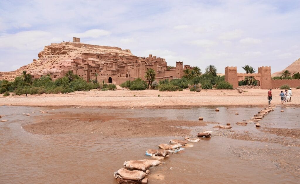 Visitors crossing the Ounila River toward the clay fortress village of Aït Ben Haddou in southern Morocco