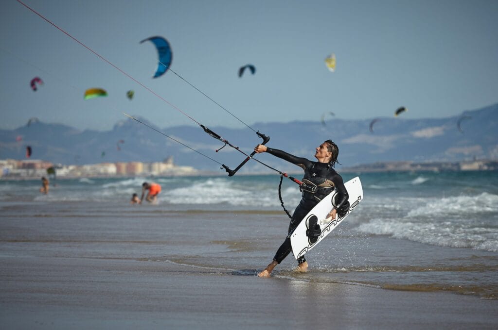Kitesurfer launching from a beach with multiple kites in the sky during the Kite-Surf World Cup in Dakhla, Morocco.