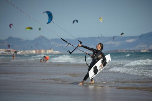 Kitesurfer launching from a beach with multiple kites in the sky during the Kite-Surf World Cup in Dakhla, Morocco.