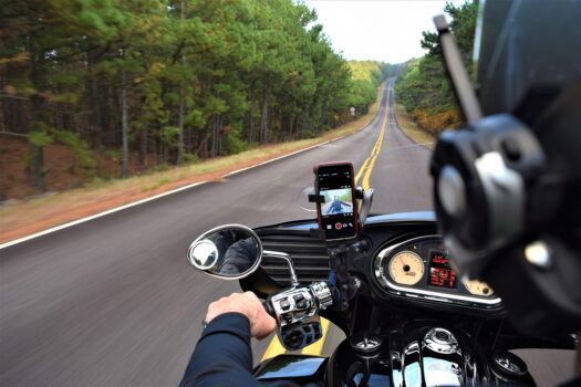 View from a motorcycle on an open highway surrounded by trees, symbolizing Morocco’s expanding and improving road network.