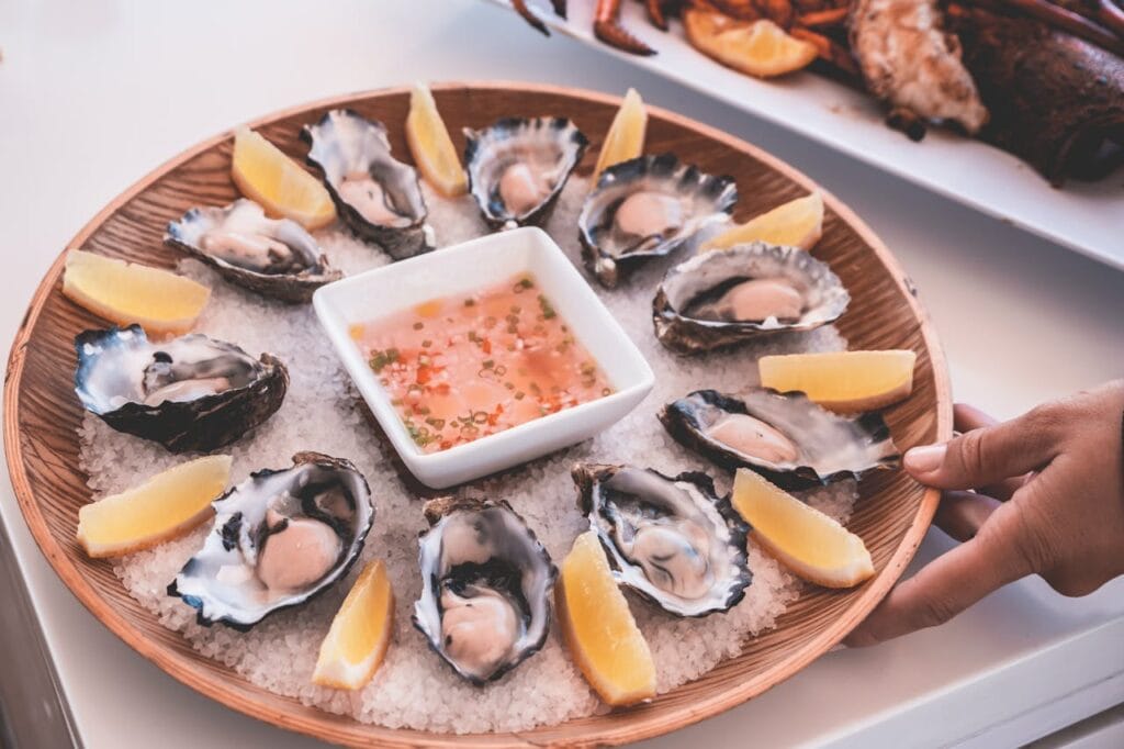 Fresh oysters on a wooden plate with lemon wedges in Oualidia, Morocco
