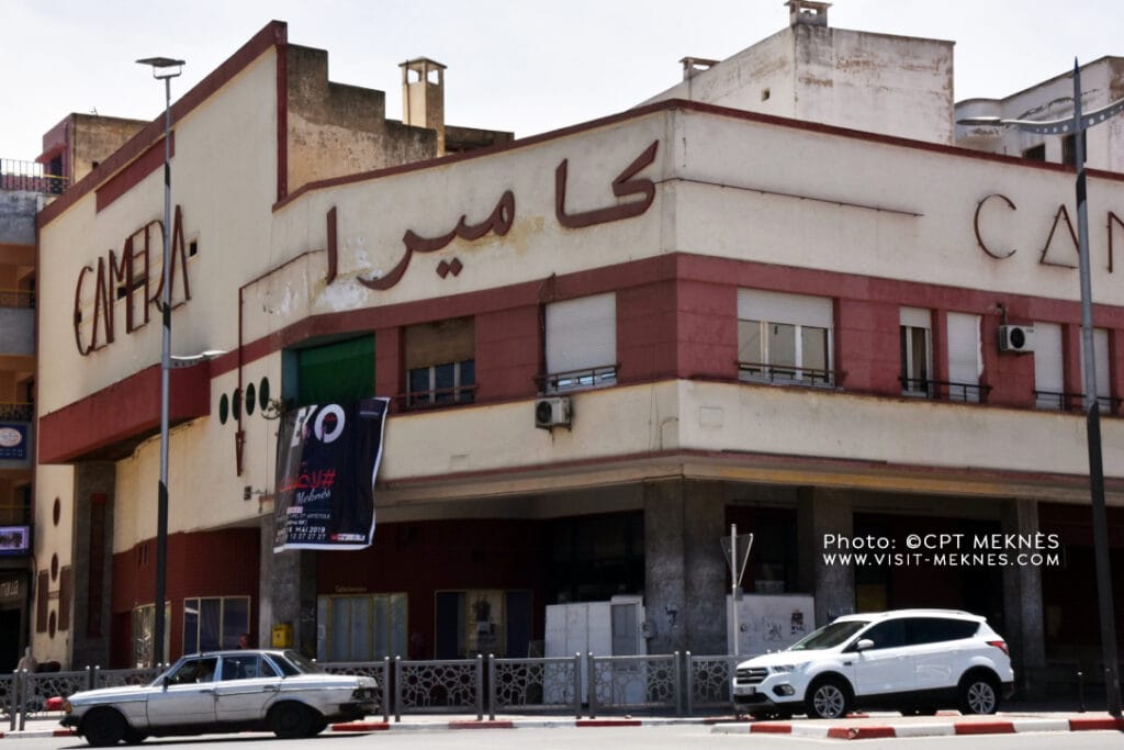 Exterior of Cinéma Caméra building in Meknès, Morocco with Arabic signage and street view