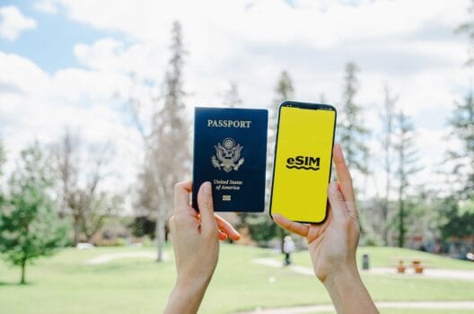 Hands holding a U.S. passport and a smartphone showing an eSIM screen, illustrating digital SIM use for easier travel in Morocco.