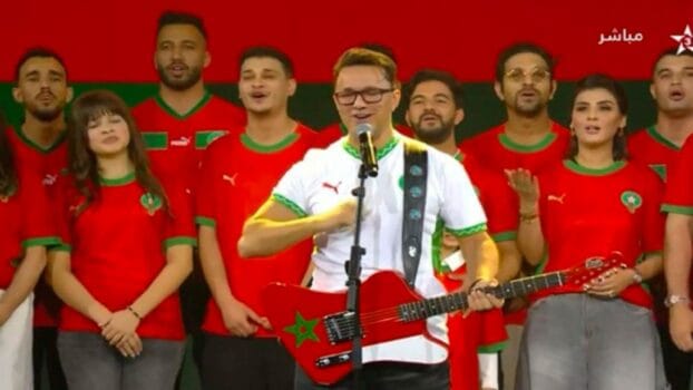 RedOne performing with Moroccan singers wearing national team jerseys during a patriotic musical performance.