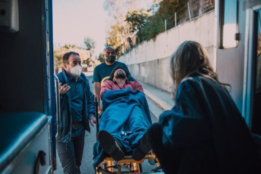 Emergency medical team assisting an injured person into an ambulance during a public event.