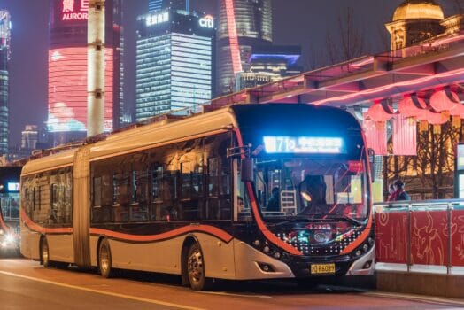 Modern articulated bus operating on a Bus Rapid Transit corridor at night, illustrating high-capacity urban mobility with dedicated stations.