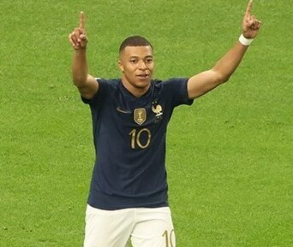 Football player celebrating a goal while wearing the France national team jersey during an international match