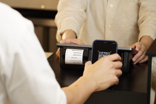 Tourist making a contactless mobile payment using QR code scanner at Moroccan hotel reception