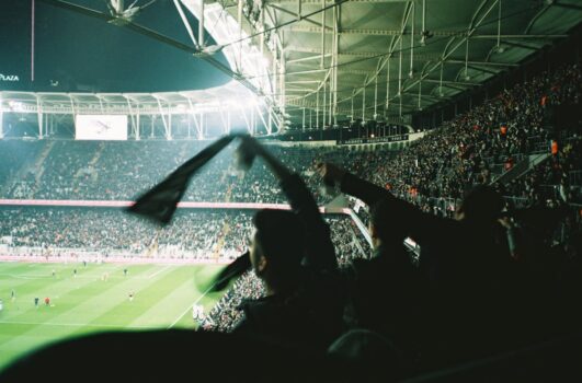 Football fans celebrating inside a packed stadium during a night match